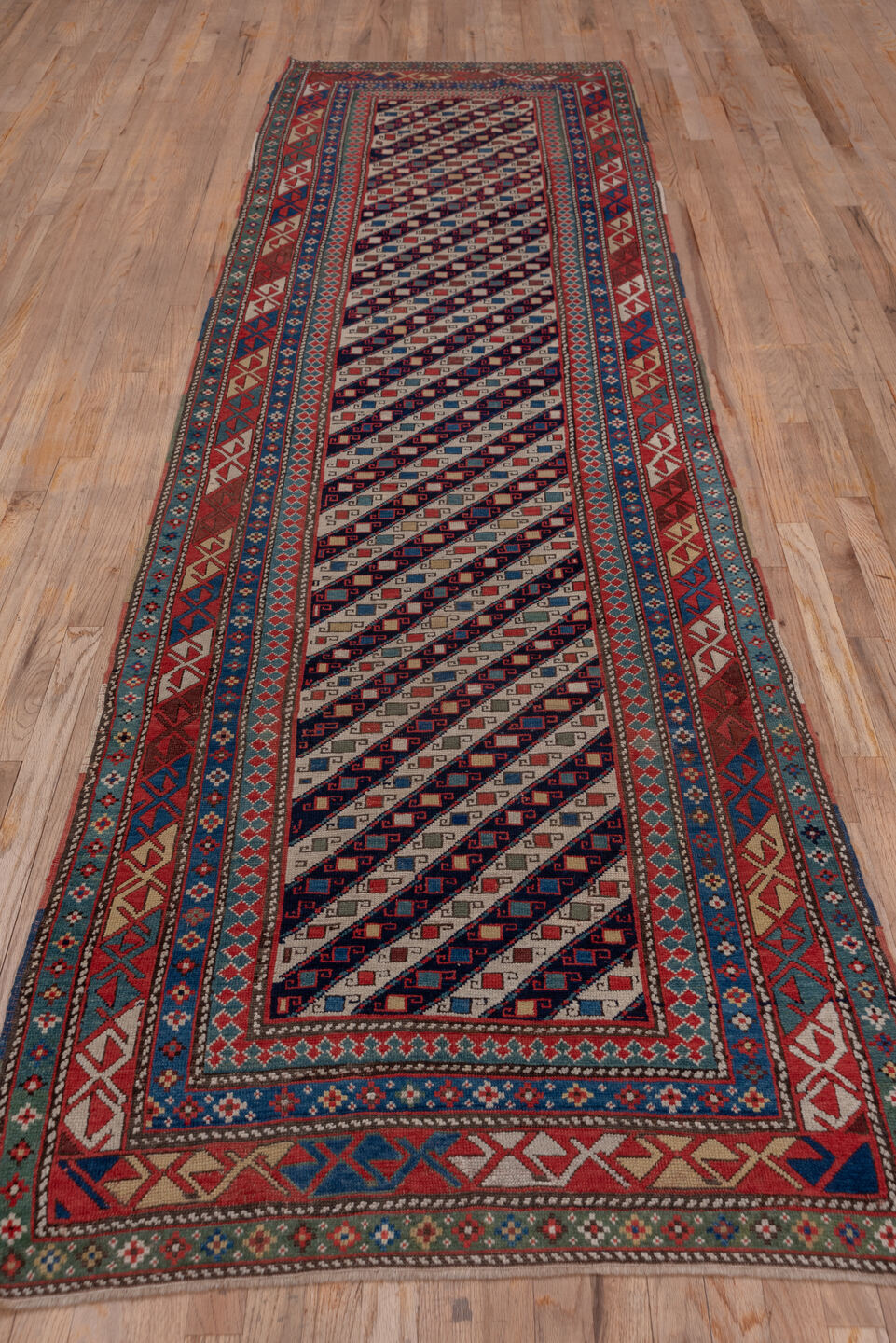 3' x 12' one-of-a-kind handmade vintage Genje runner rug. Color palette: black, blue, brown, gray, pink, red