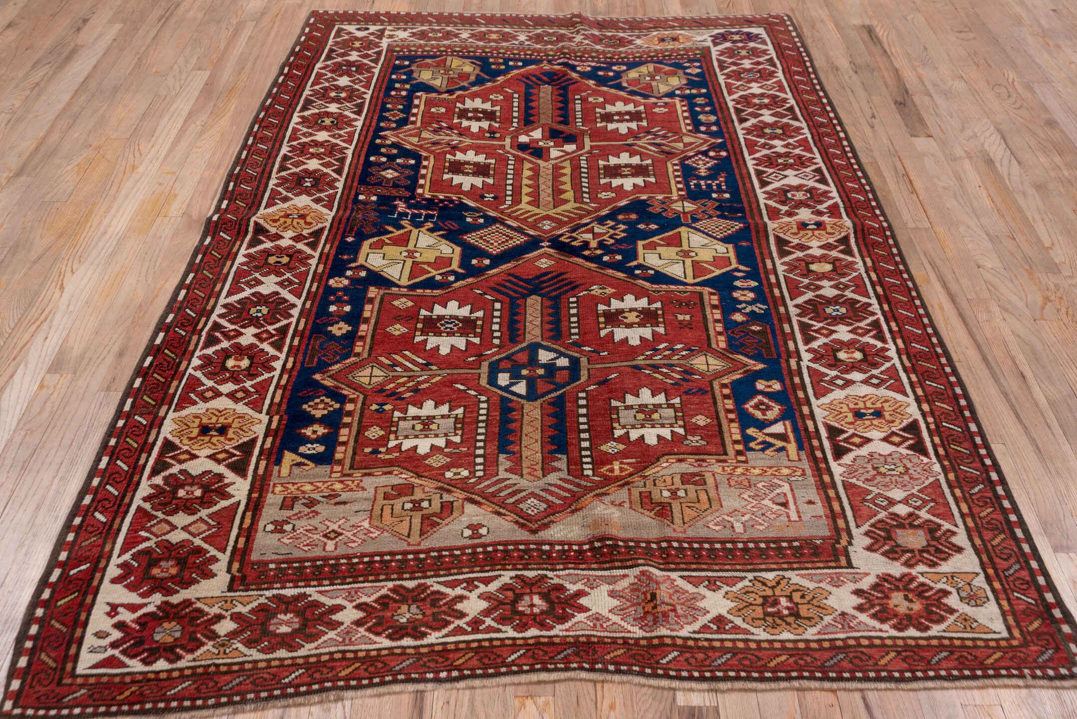 5' x 7' one-of-a-kind handmade antique Trans Caucasian rug. Color palette: rust, ivory, navy, burgundy, camel, crimson, gold