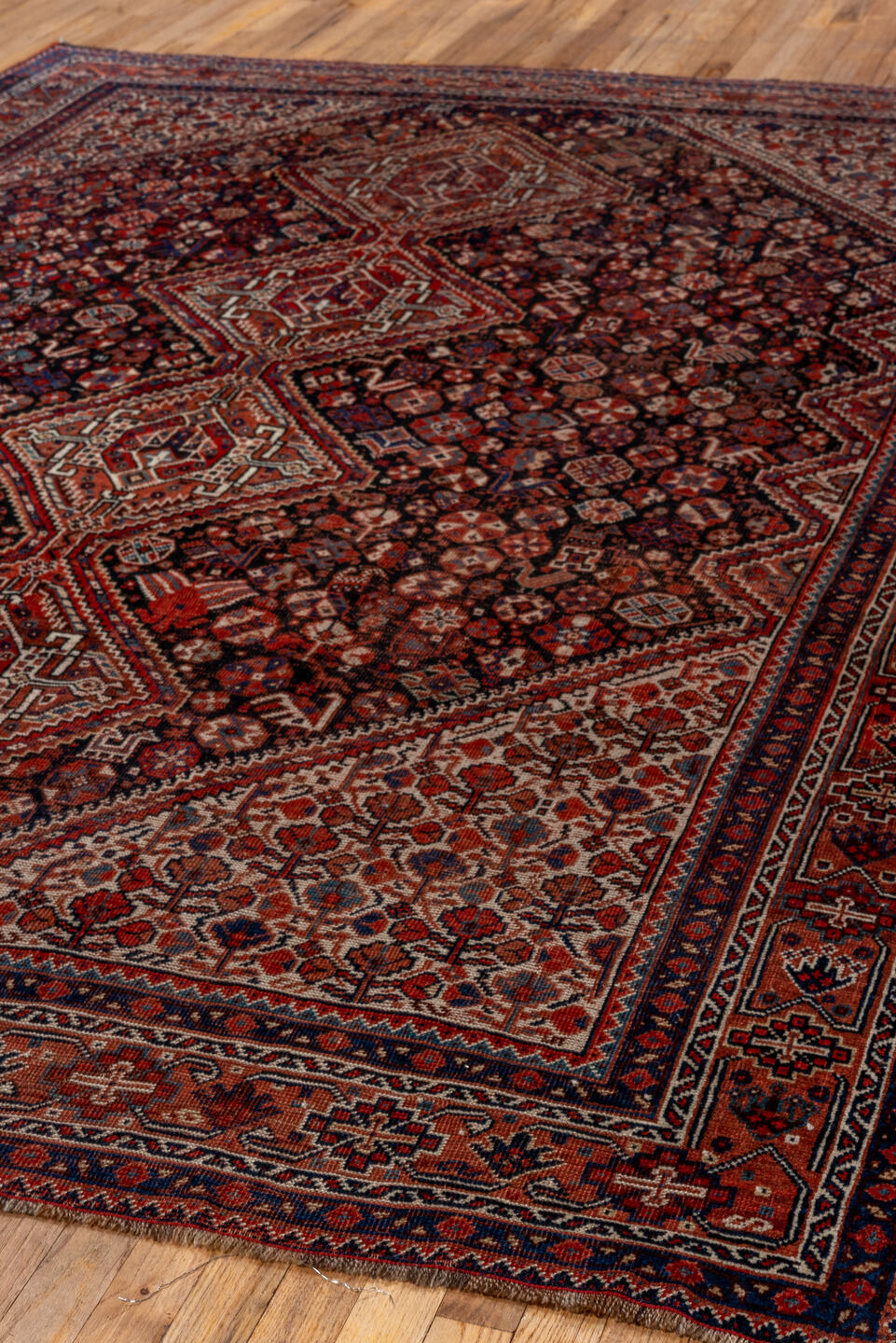 7' x 9' one-of-a-kind handmade antique Shiraz rug. Color palette: rust, navy, ivory, burgundy, terracotta, indigo, camel