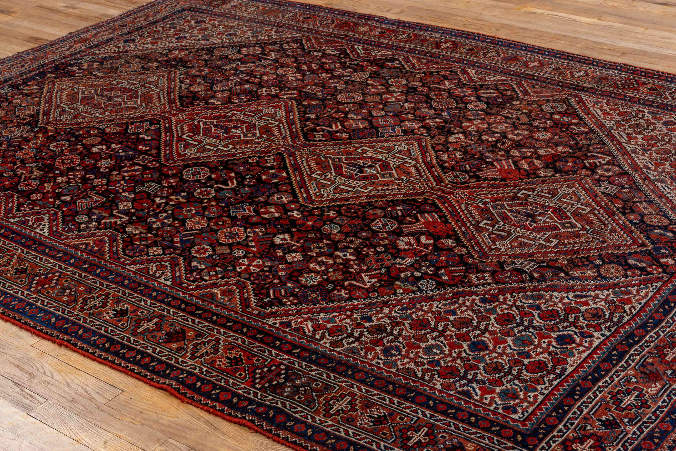 7' x 9' one-of-a-kind handmade antique Shiraz rug. Color palette: rust, navy, ivory, burgundy, terracotta, indigo, camel