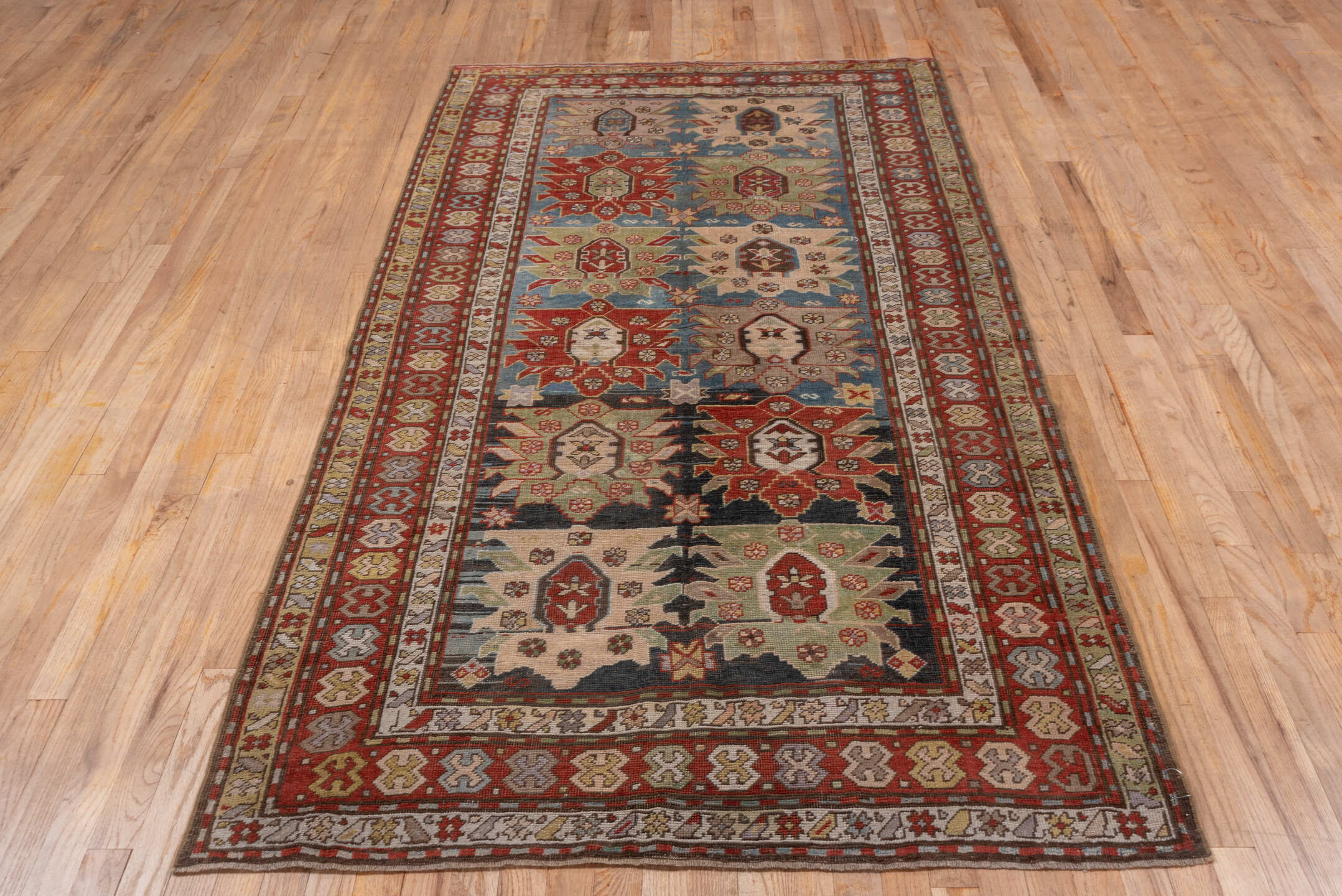 4' x 8' one-of-a-kind handmade antique Caucasian rug. Color palette: ivory, rust, brick, slate, sky_blue, camel, charcoal