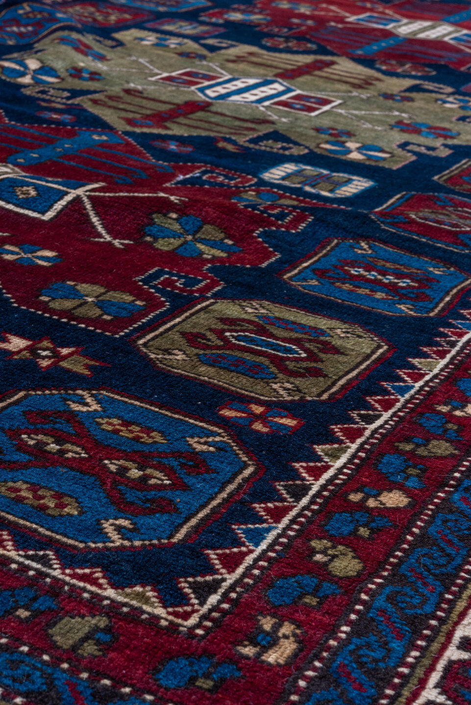 4' x 7' one-of-a-kind handmade antique Caucasian rug. Color palette: navy, crimson, ivory, cobalt, burgundy, camel, saffron