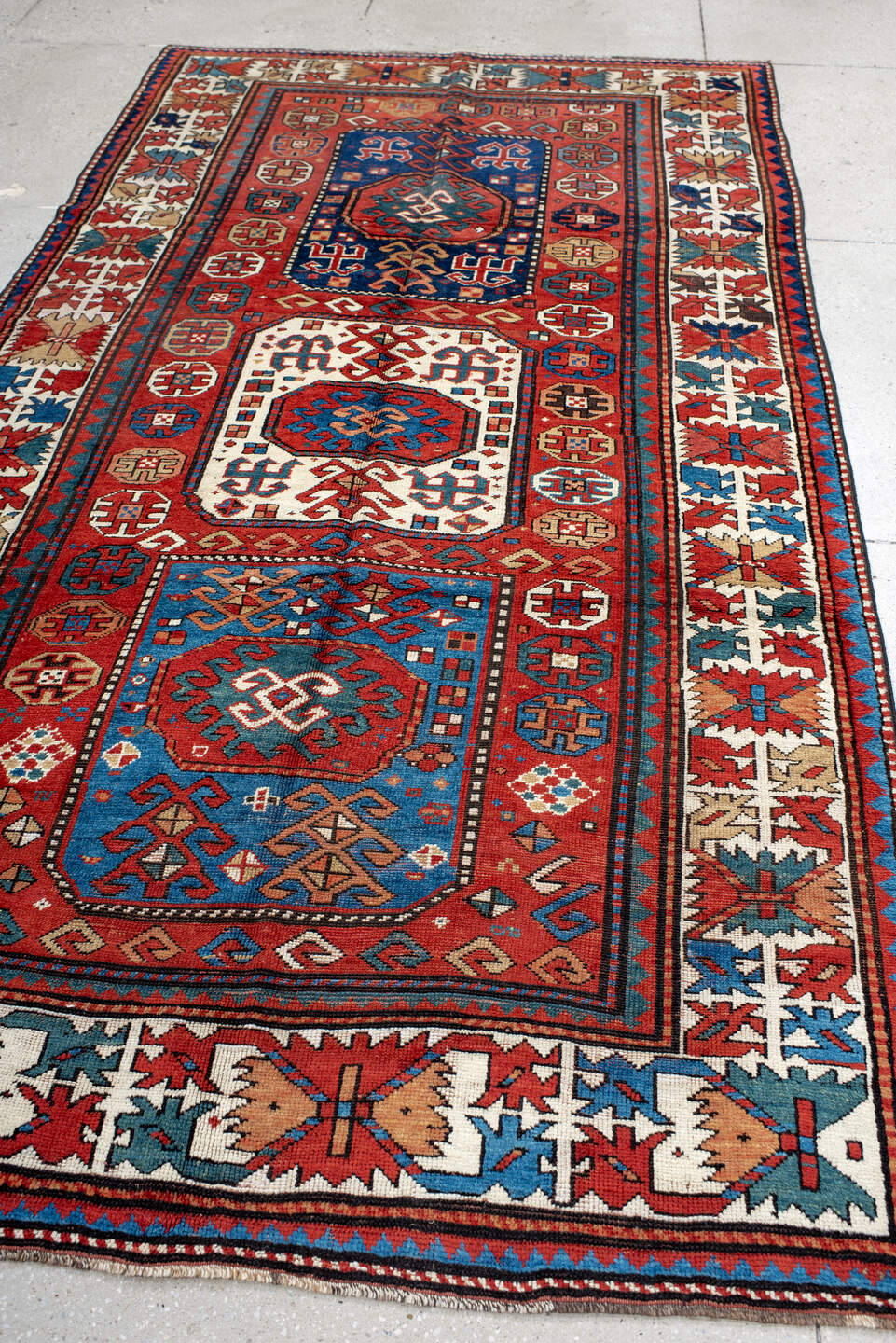 5' x 10' one-of-a-kind handmade antique Kazak medium size rug. Color palette: red, ivory, blue, teal, navy, rust, cream