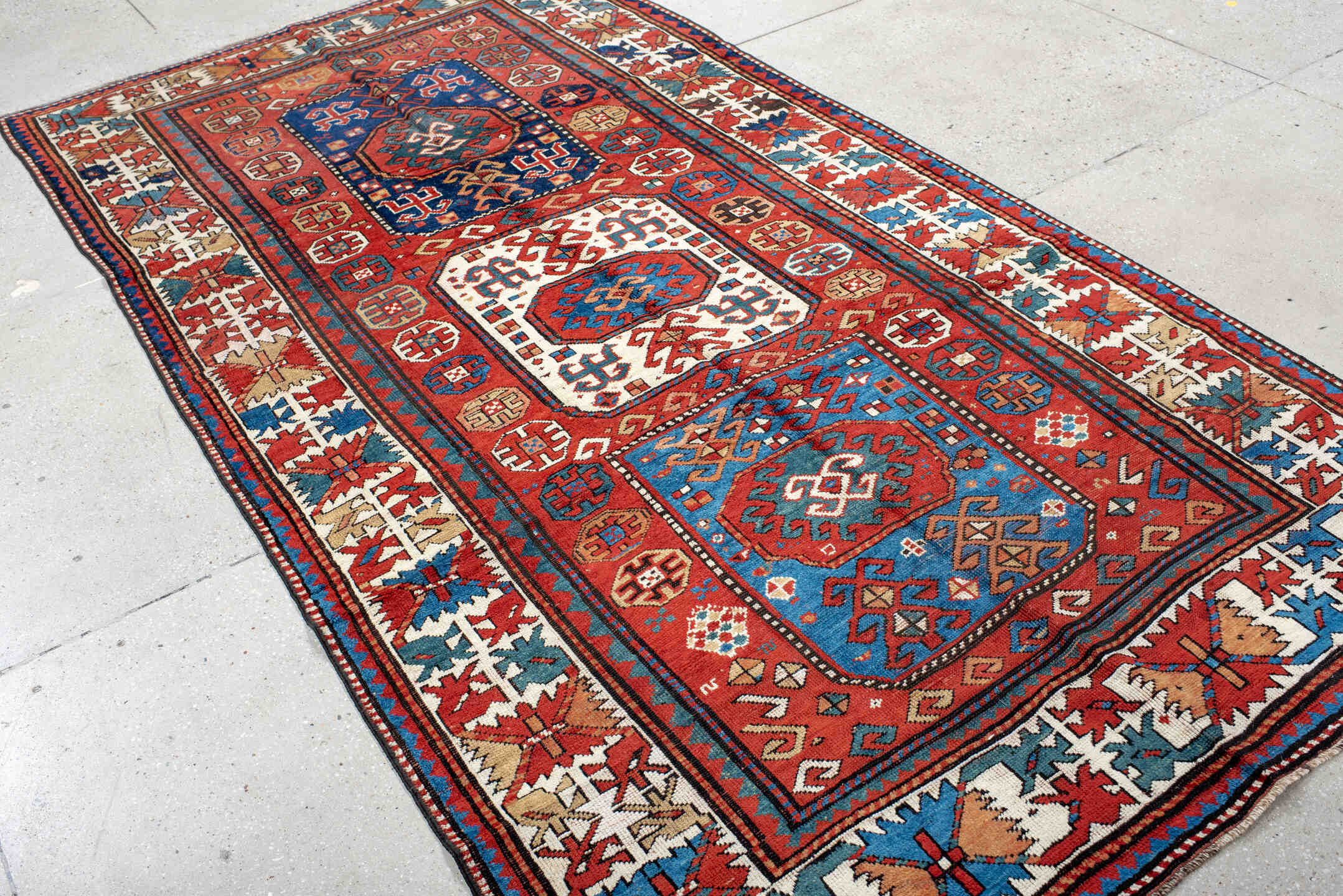 5' x 10' one-of-a-kind handmade antique Kazak medium size rug. Color palette: red, ivory, blue, teal, navy, rust, cream