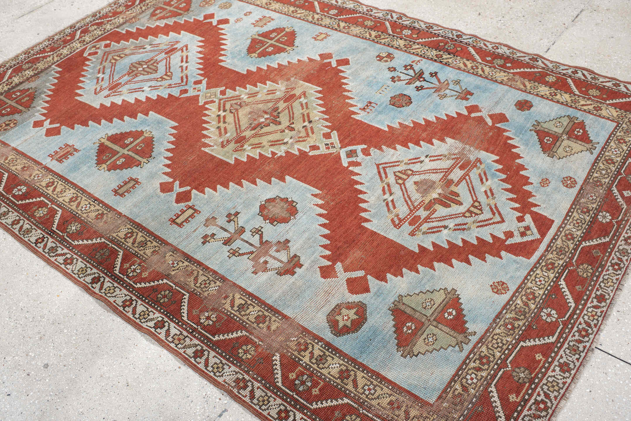 5' x 7' one-of-a-kind handmade antique Caucasian rug. Color palette: rust, sky blue, ivory, camel, taupe, crimson