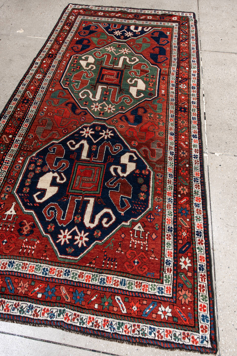 4' x 8' one-of-a-kind handmade antique Kazak rug. Color palette: rust, navy, ivory, sage, crimson, teal, rose, terracotta