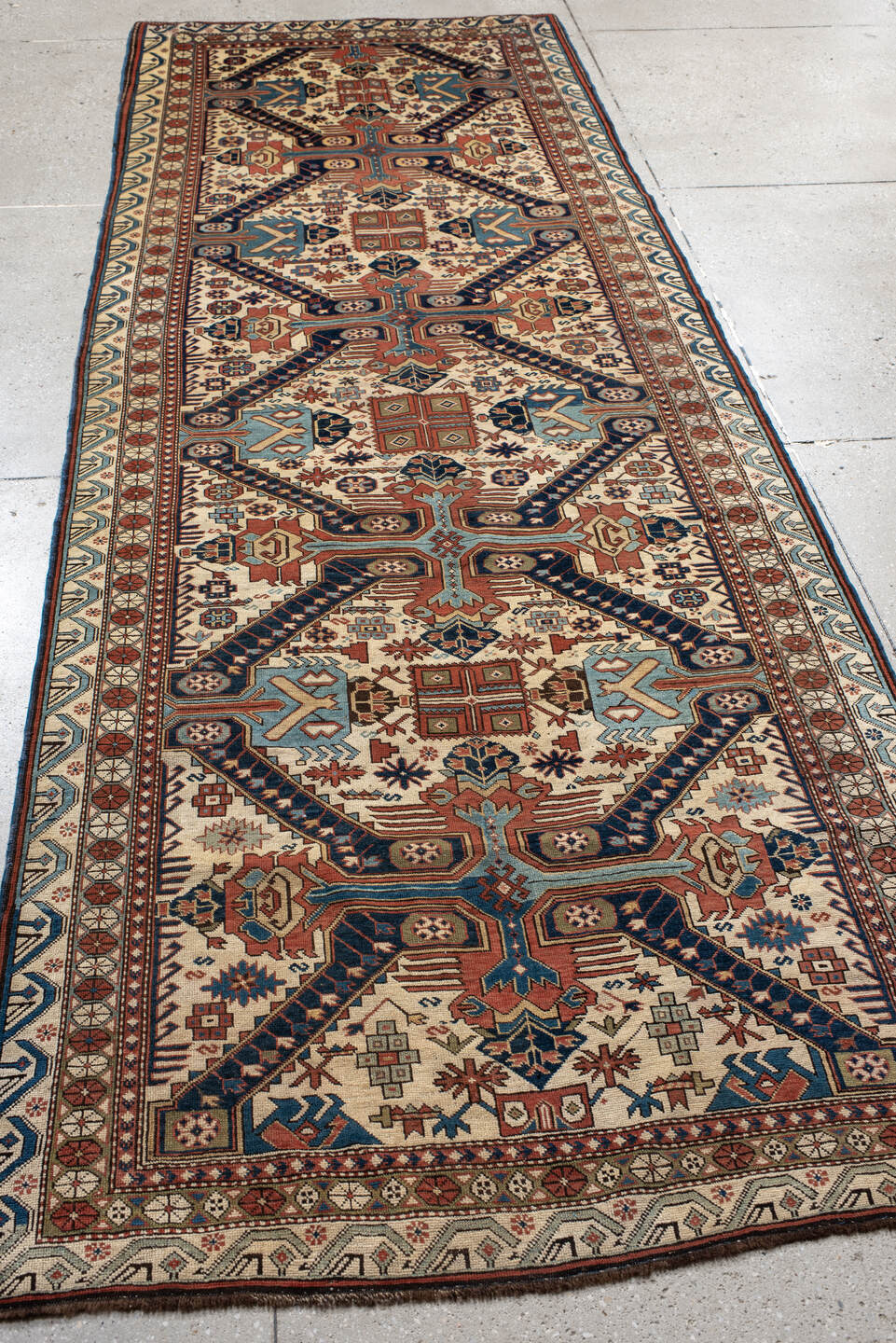4' x 11' one-of-a-kind handmade antique Caucasian runner rug. Color palette: ivory, indigo, rust, sky blue, navy, camel