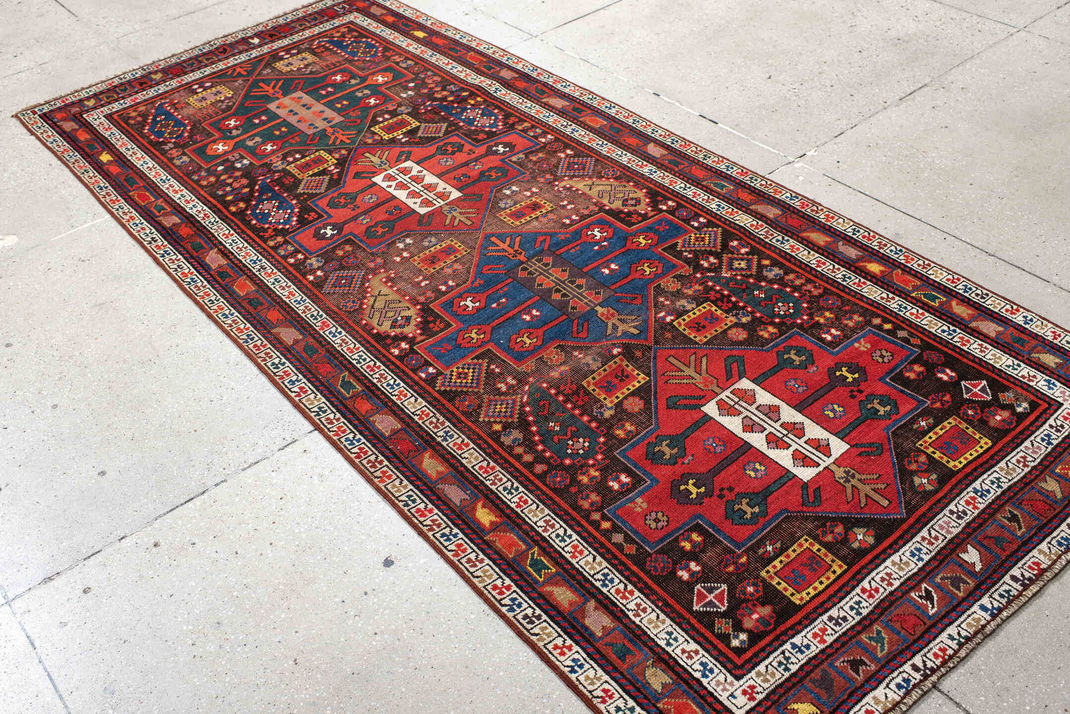 3' x 8' one-of-a-kind handmade antique Caucasian runner rug. Color palette: rust, ivory, navy, indigo, camel, crimson