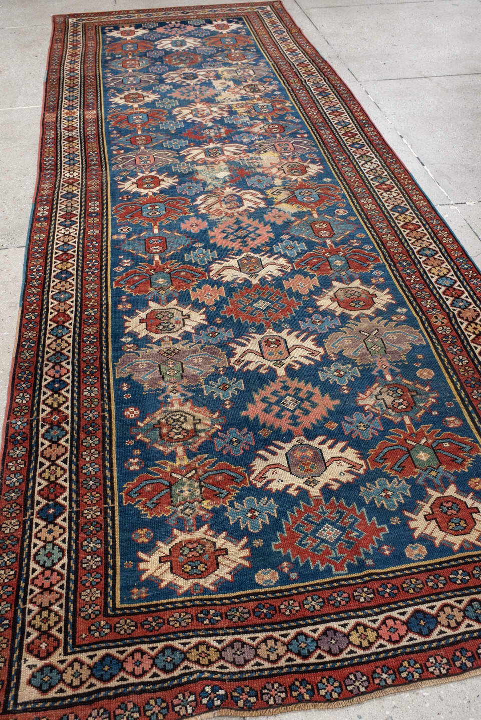 4' x 11' one-of-a-kind handmade vintage Caucasian runner rug. Color palette: blue, rust, ivory, indigo, terra cotta, camel