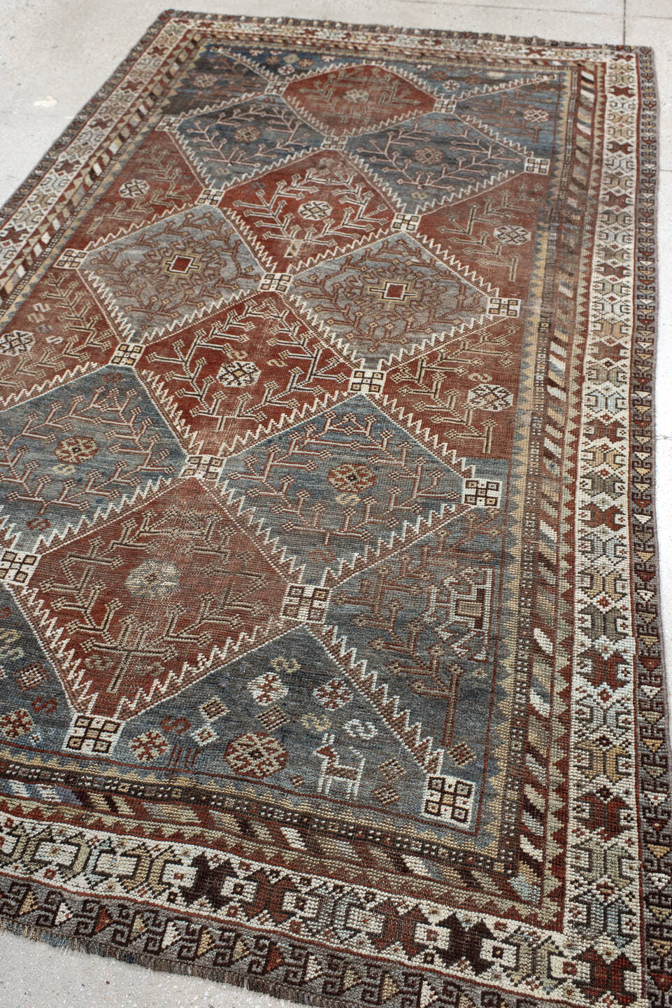 4' x 9' one-of-a-kind handmade antique Shiraz rug. Color palette: rust, sky blue, ivory, brown, taupe, charcoal, terracotta