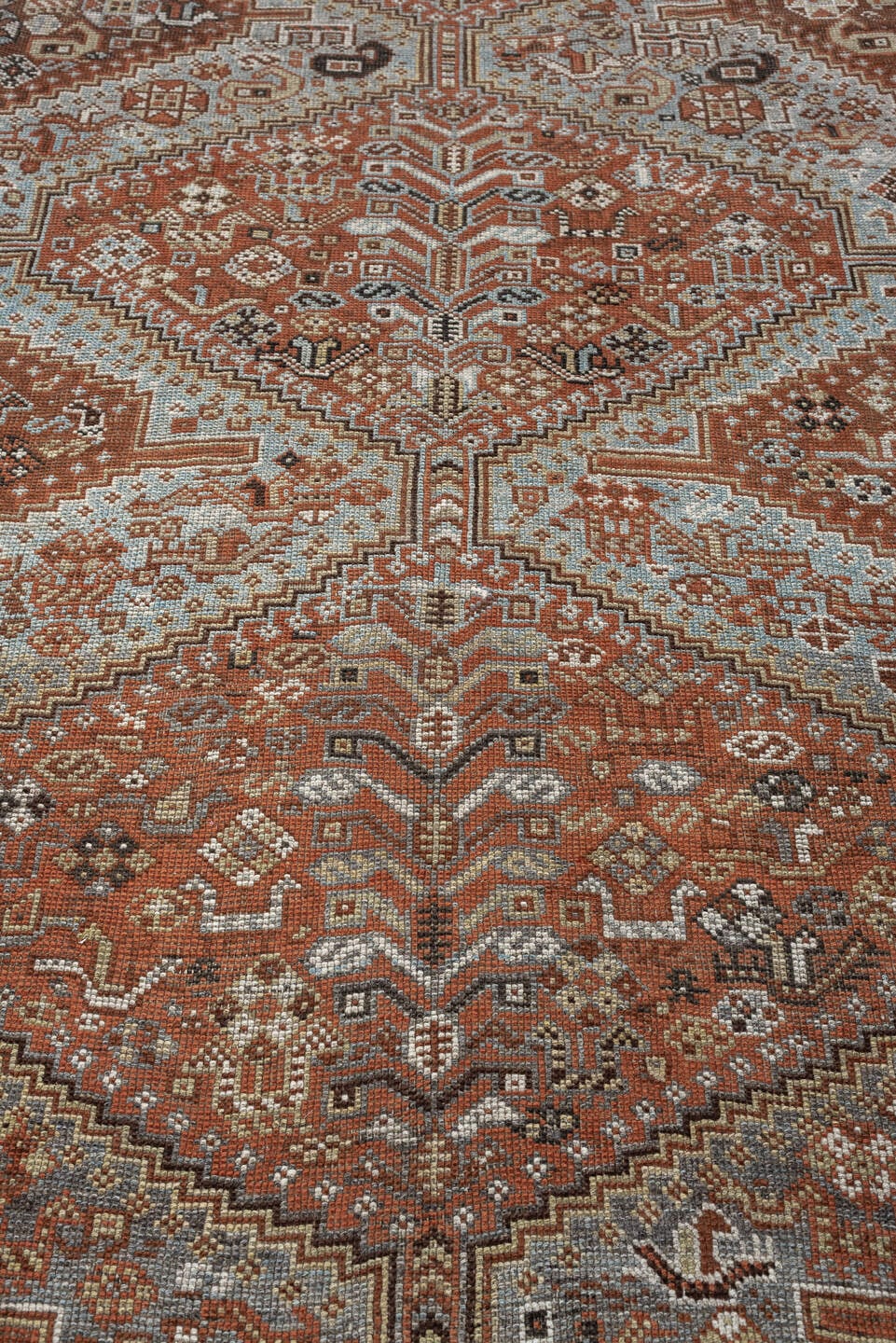 7' x 9' one-of-a-kind handmade antique Shiraz rug. Color palette: rust, pale blue gray, ivory, charcoal, terracotta, camel