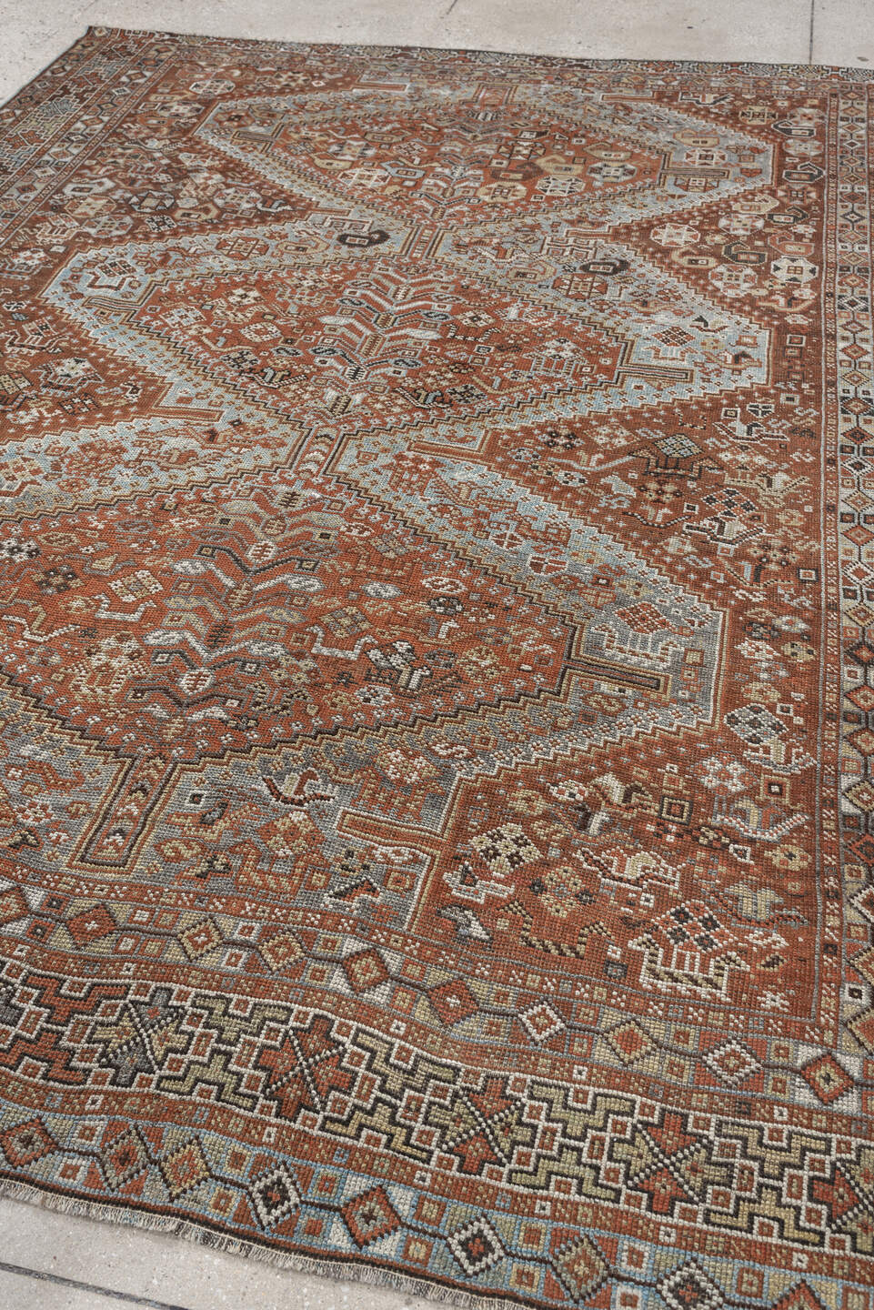 7' x 9' one-of-a-kind handmade antique Shiraz rug. Color palette: rust, pale blue gray, ivory, charcoal, terracotta, camel