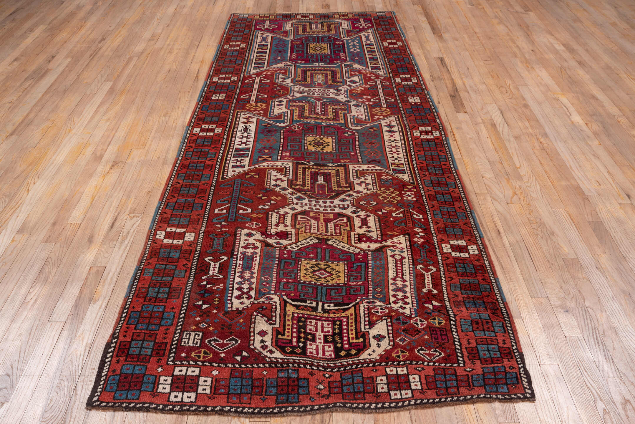 4' x 10' one-of-a-kind handmade antique Caucasian runner rug. Color palette: rust, ivory, indigo, crimson, sky_blue, gold