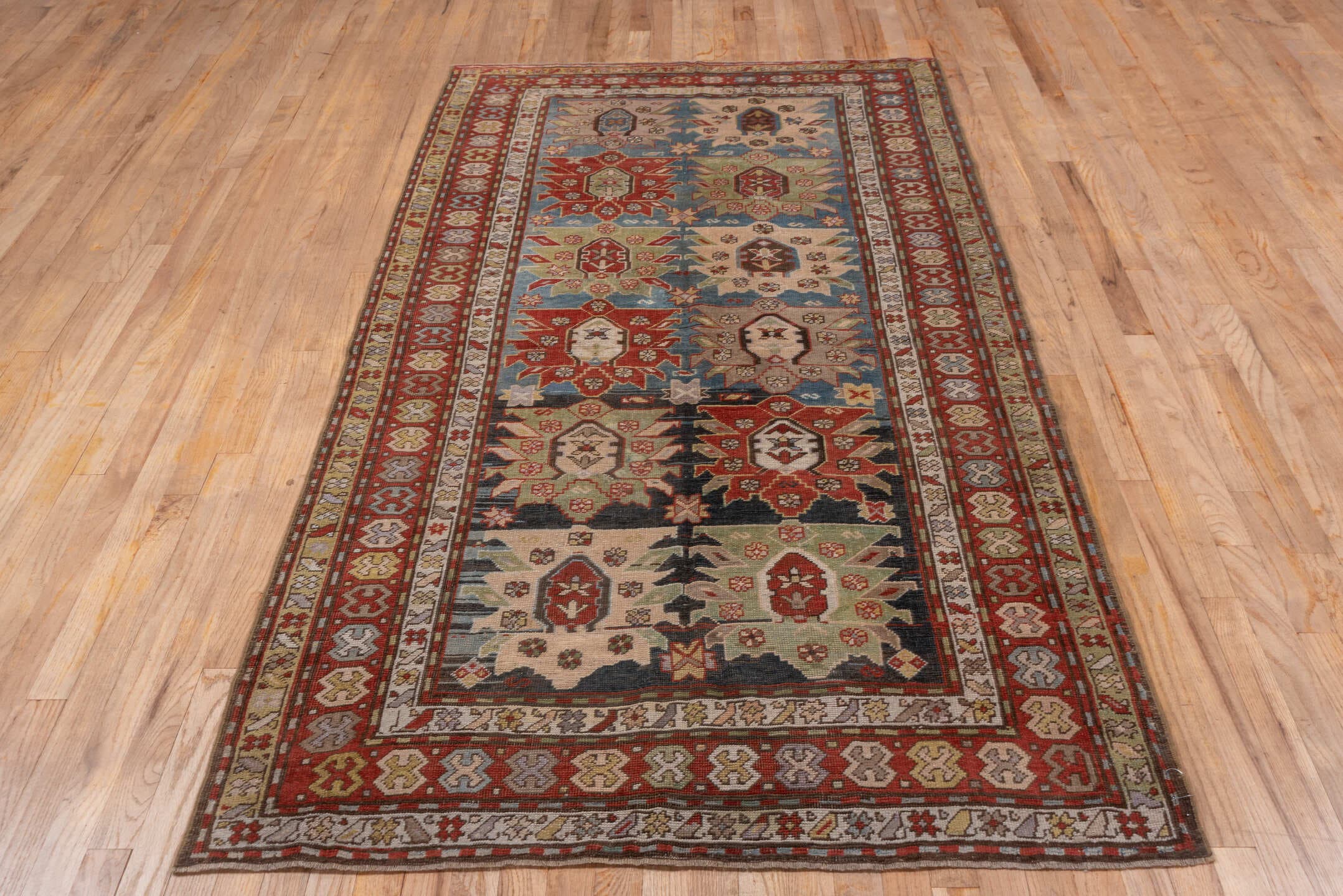 4' x 8' one-of-a-kind handmade antique Caucasian rug. Color palette: ivory, rust, brick, slate, sky_blue, camel, charcoal