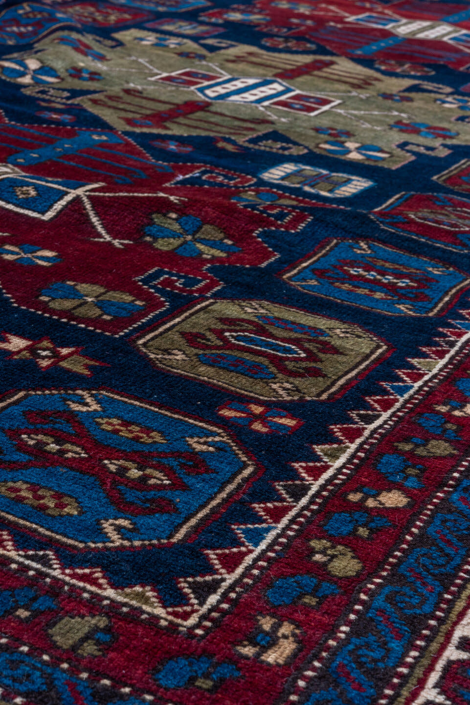 4' x 7' one-of-a-kind handmade antique Caucasian rug. Color palette: navy, crimson, ivory, cobalt, burgundy, camel, saffron