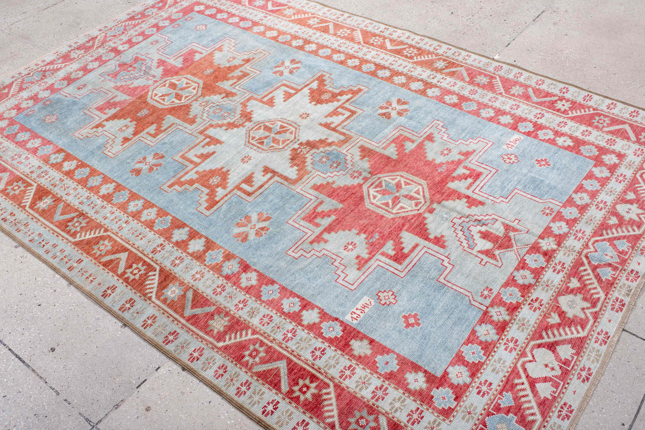 5' x 7' one-of-a-kind handmade antique Caucasian rug. Color palette: sky blue, coral, ivory, brick red, pale blue