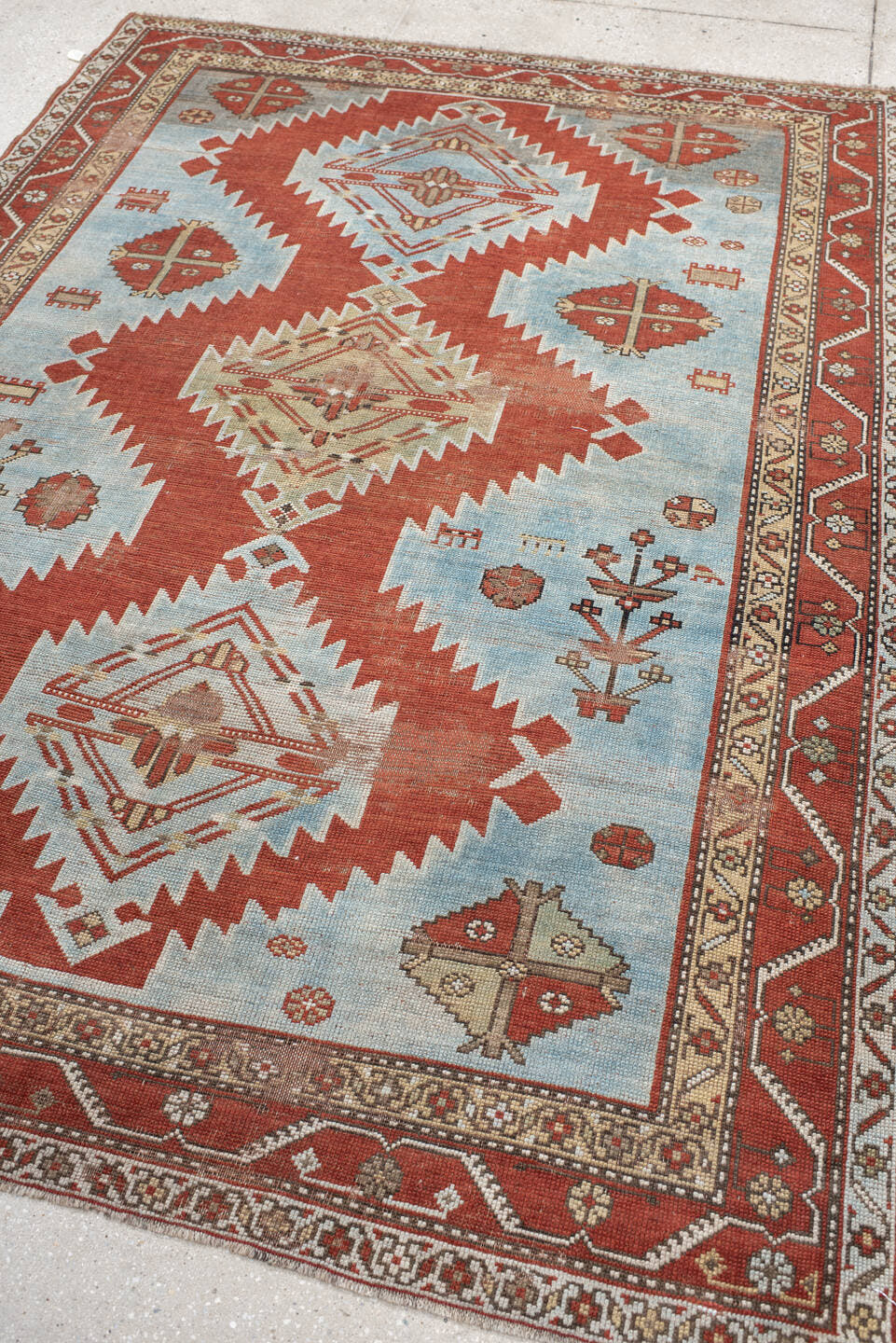 5' x 7' one-of-a-kind handmade antique Caucasian rug. Color palette: rust, sky blue, ivory, camel, taupe, crimson