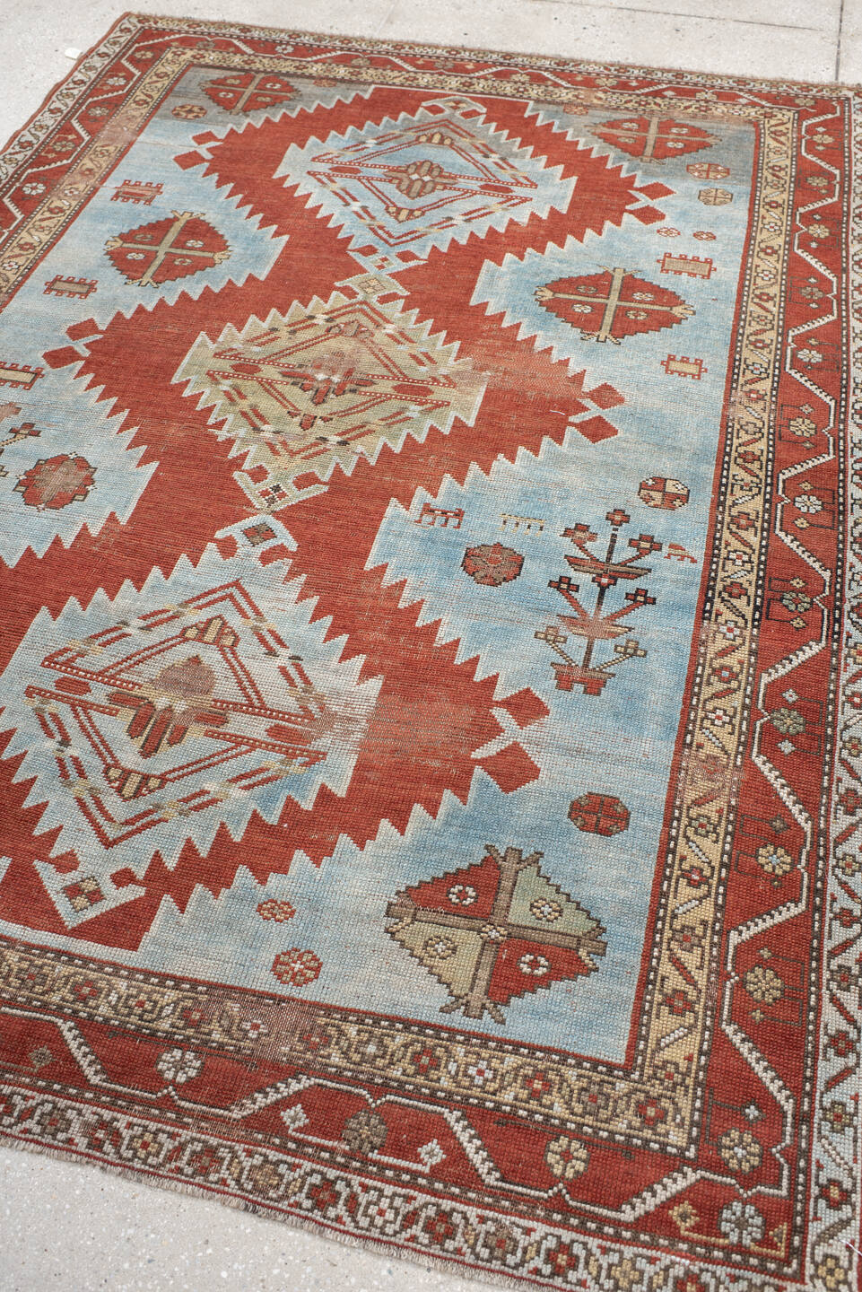 5' x 7' one-of-a-kind handmade antique Caucasian rug. Color palette: rust, sky blue, ivory, camel, taupe, crimson