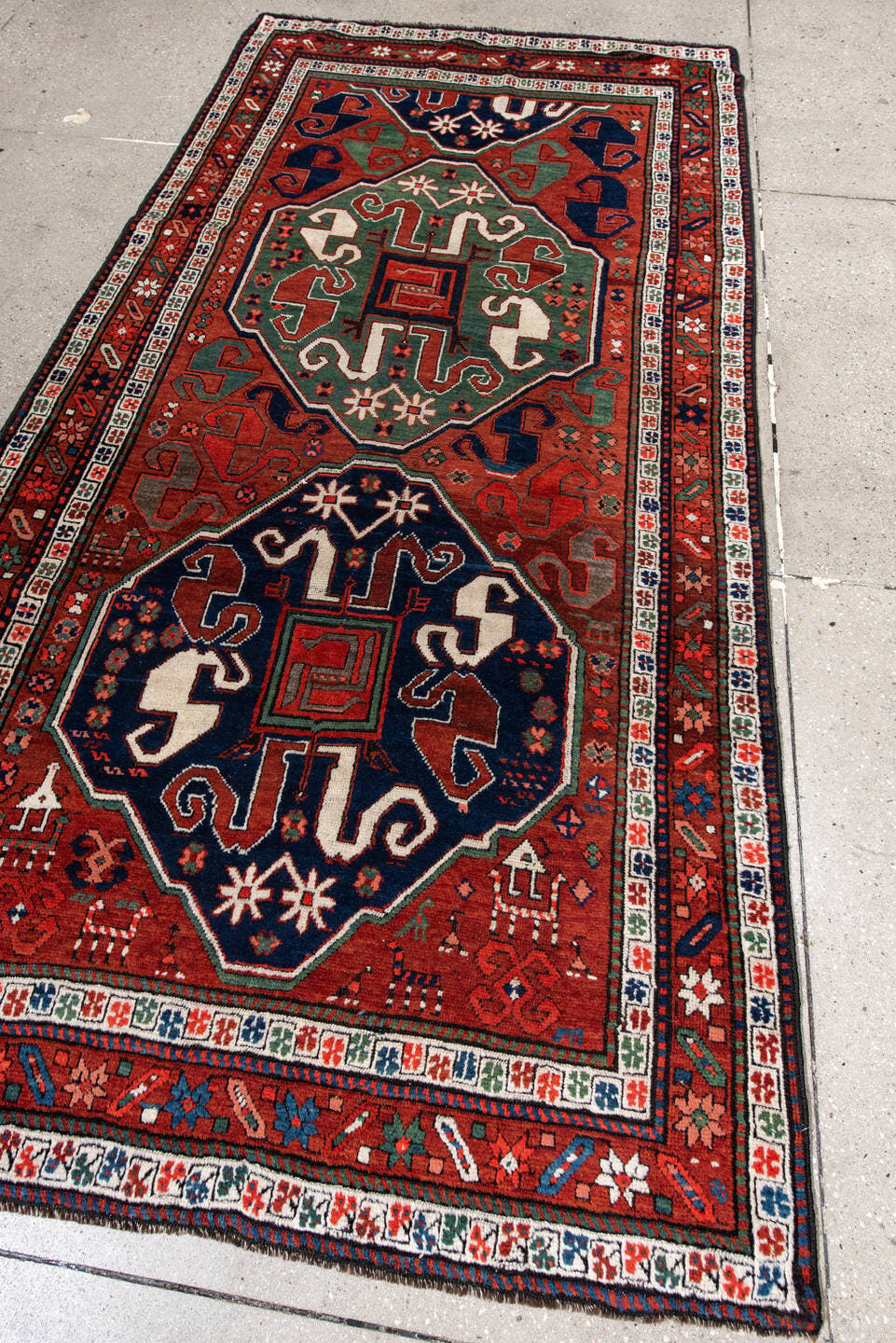 4' x 8' one-of-a-kind handmade antique Kazak rug. Color palette: rust, navy, ivory, sage, crimson, teal, rose, terracotta