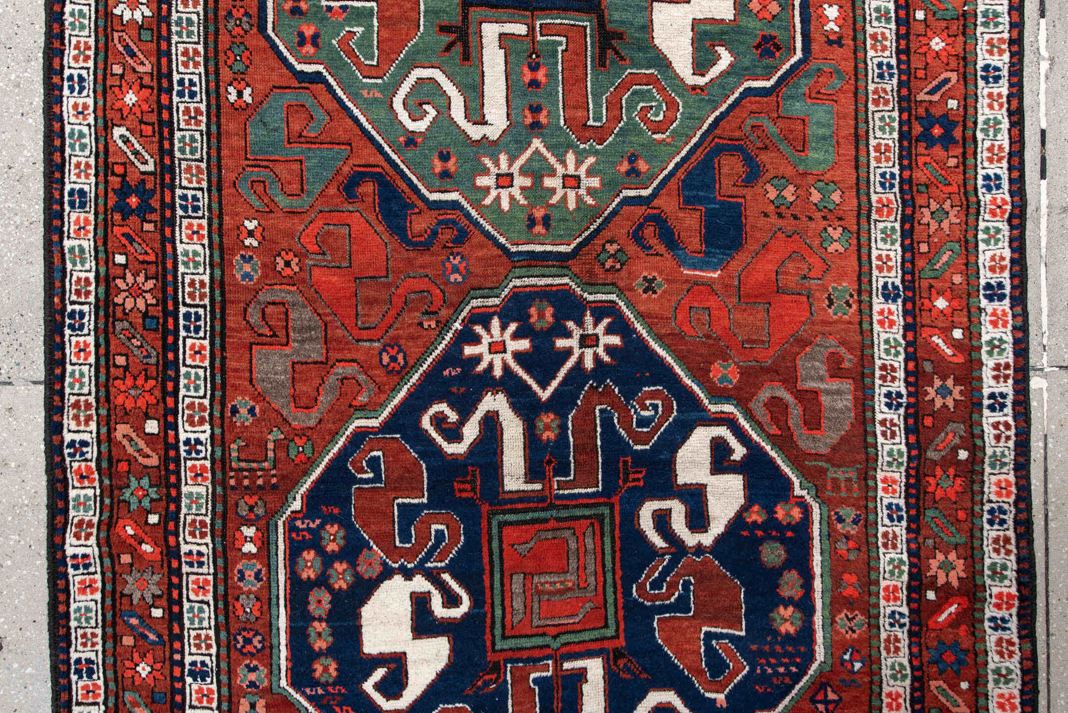 4' x 8' one-of-a-kind handmade antique Kazak rug. Color palette: rust, navy, ivory, sage, crimson, teal, rose, terracotta