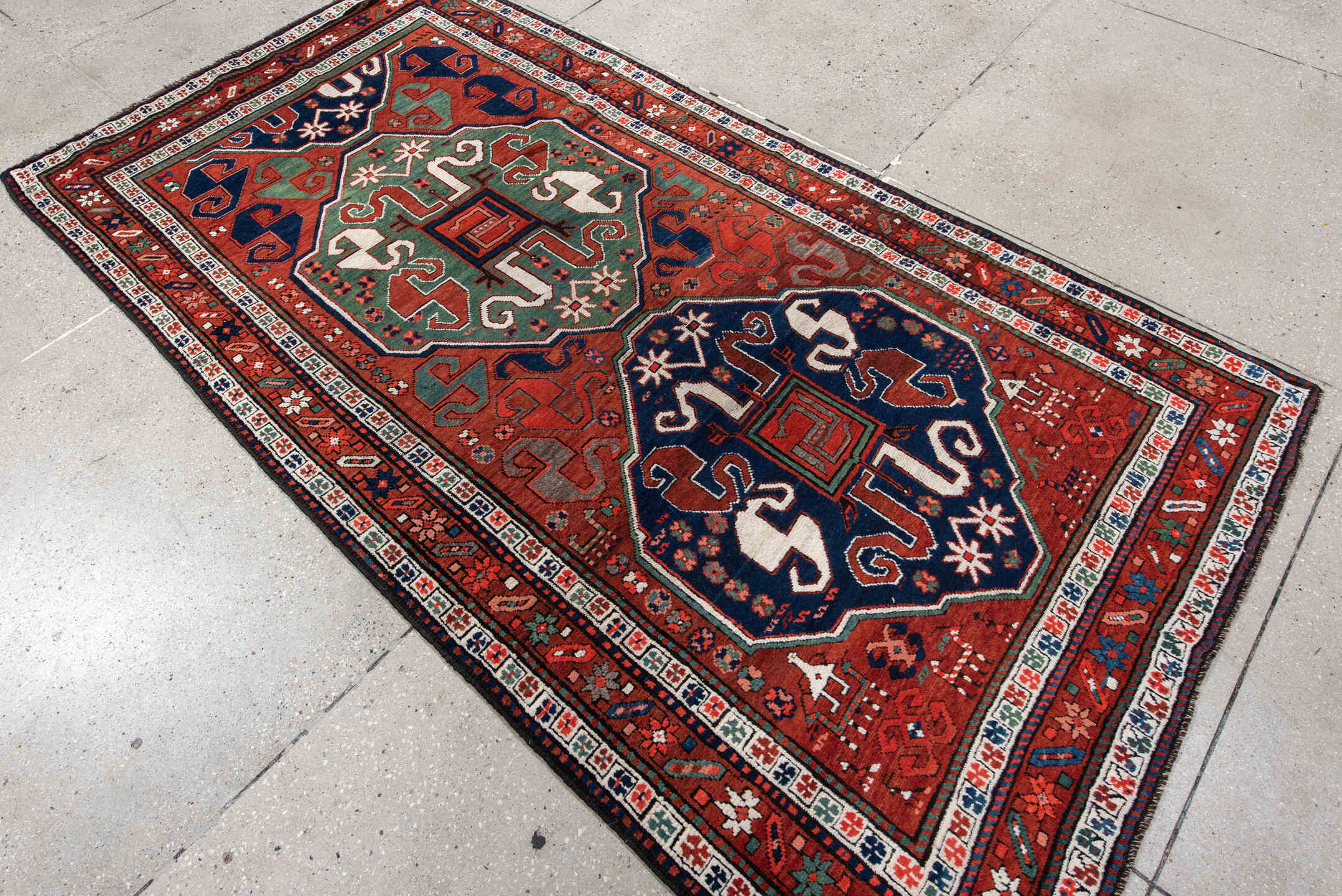 4' x 8' one-of-a-kind handmade antique Kazak rug. Color palette: rust, navy, ivory, sage, crimson, teal, rose, terracotta