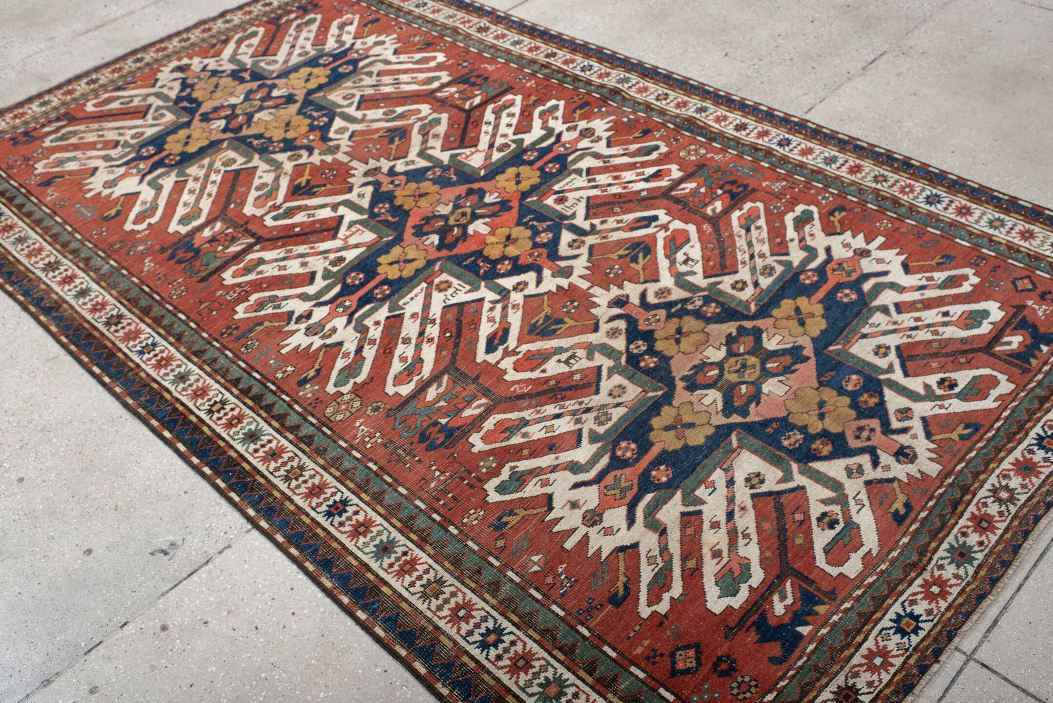 5' x 8' one-of-a-kind handmade antique Kazak medium size rug. Color palette: rust, ivory, navy, sage, gold, crimson, rose