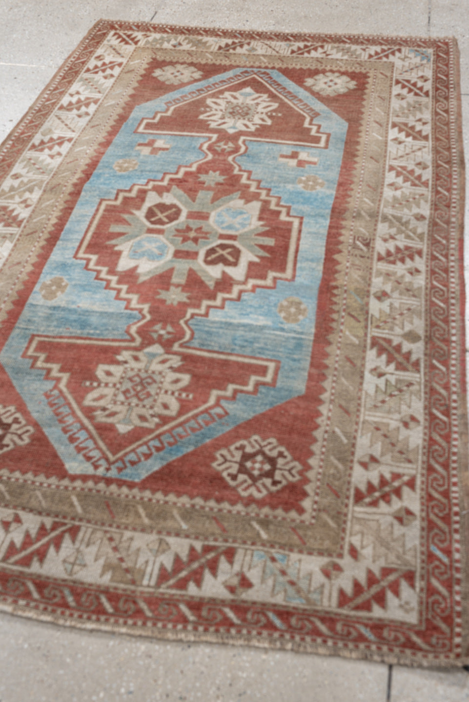 6' x 4' one-of-a-kind handmade antique Caucasian rug. Color palette: terracotta, ivory, sky blue, taupe, camel, brown