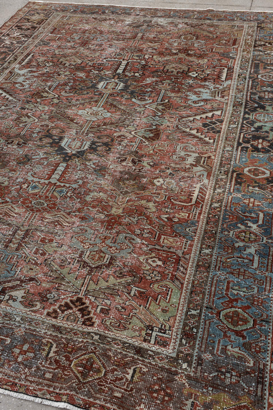 7' x 9' one-of-a-kind handmade antique Heriz rug. Color palette: rust, ivory, sky blue, charcoal, taupe, camel, brown