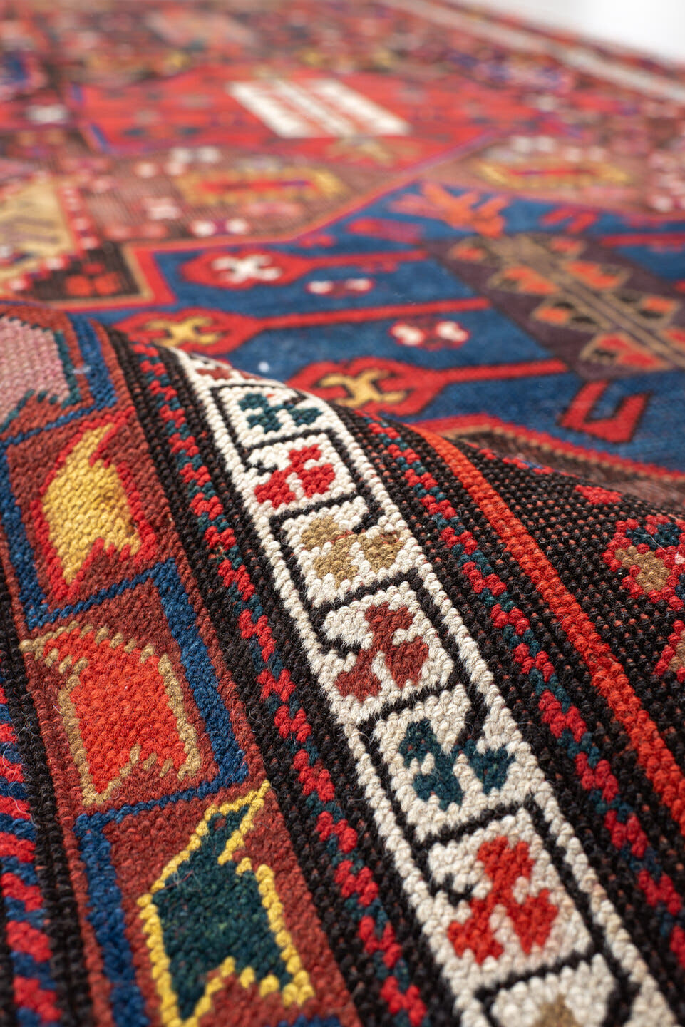 3' x 8' one-of-a-kind handmade antique Caucasian runner rug. Color palette: rust, ivory, navy, indigo, camel, crimson