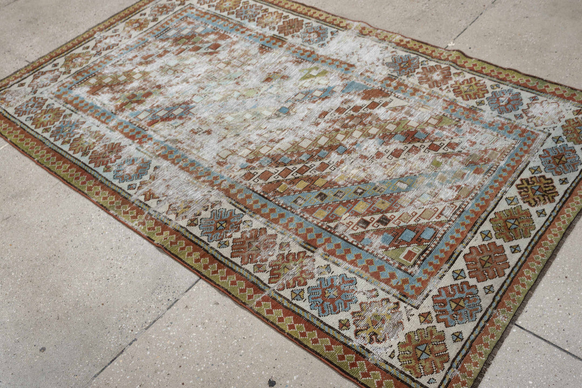 4' x 6' one-of-a-kind handmade antique Caucasian rug. Color palette: ivory, rust, sky blue, olive, camel, taupe, brown