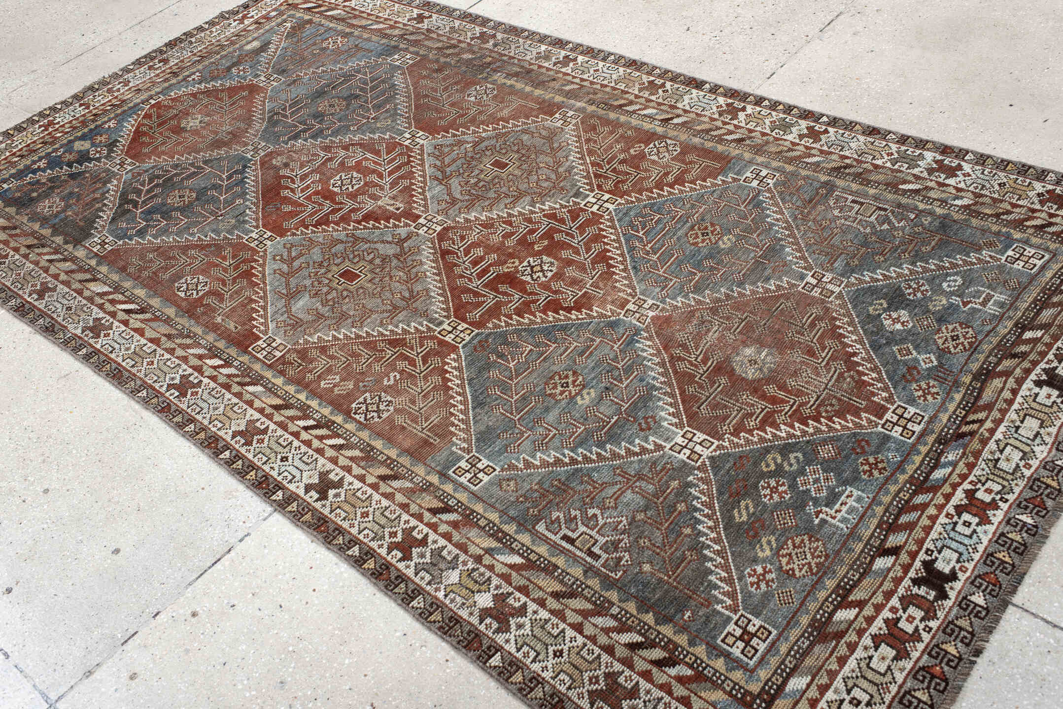 4' x 9' one-of-a-kind handmade antique Shiraz rug. Color palette: rust, sky blue, ivory, brown, taupe, charcoal, terracotta
