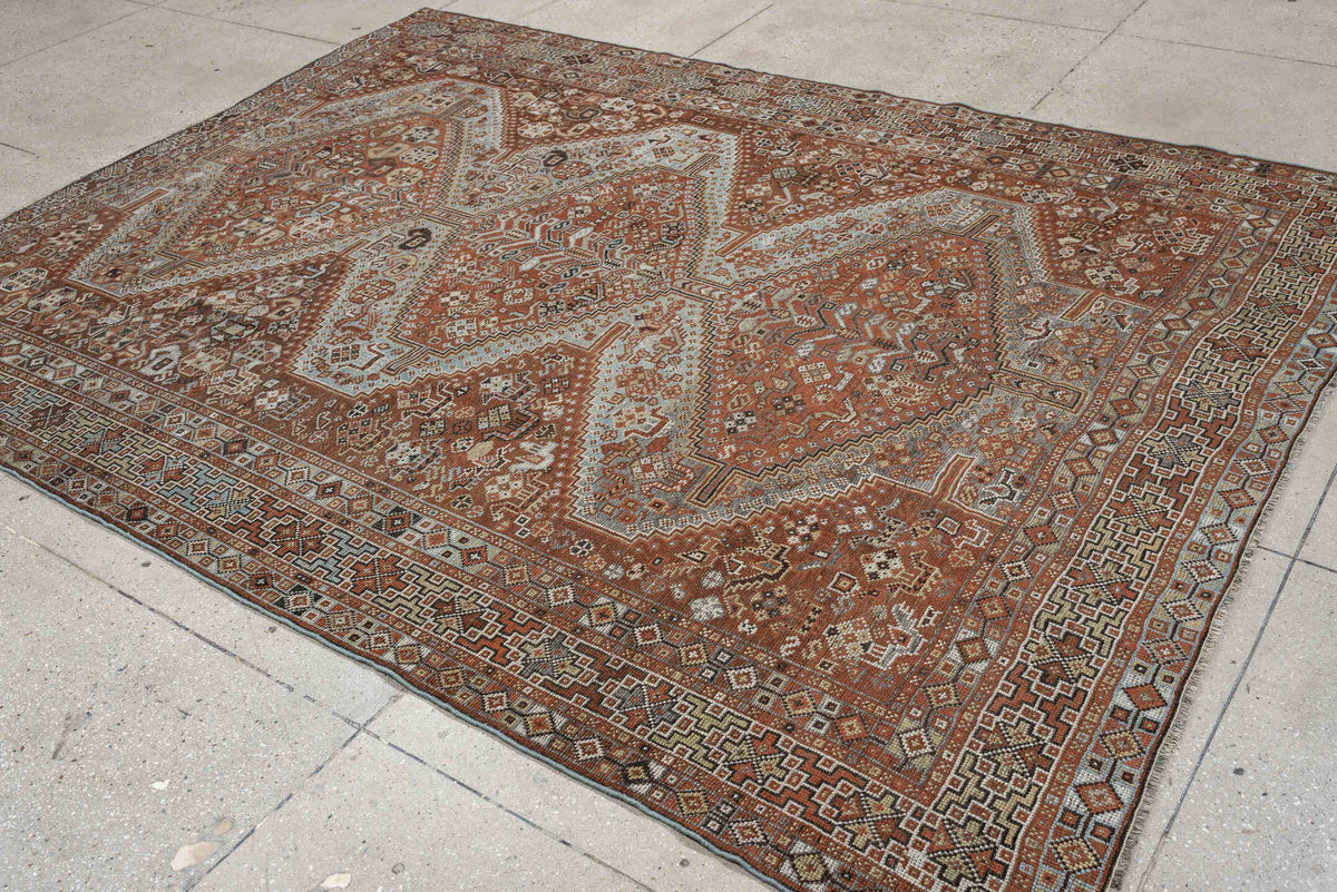 7' x 9' one-of-a-kind handmade antique Shiraz rug. Color palette: rust, pale blue gray, ivory, charcoal, terracotta, camel