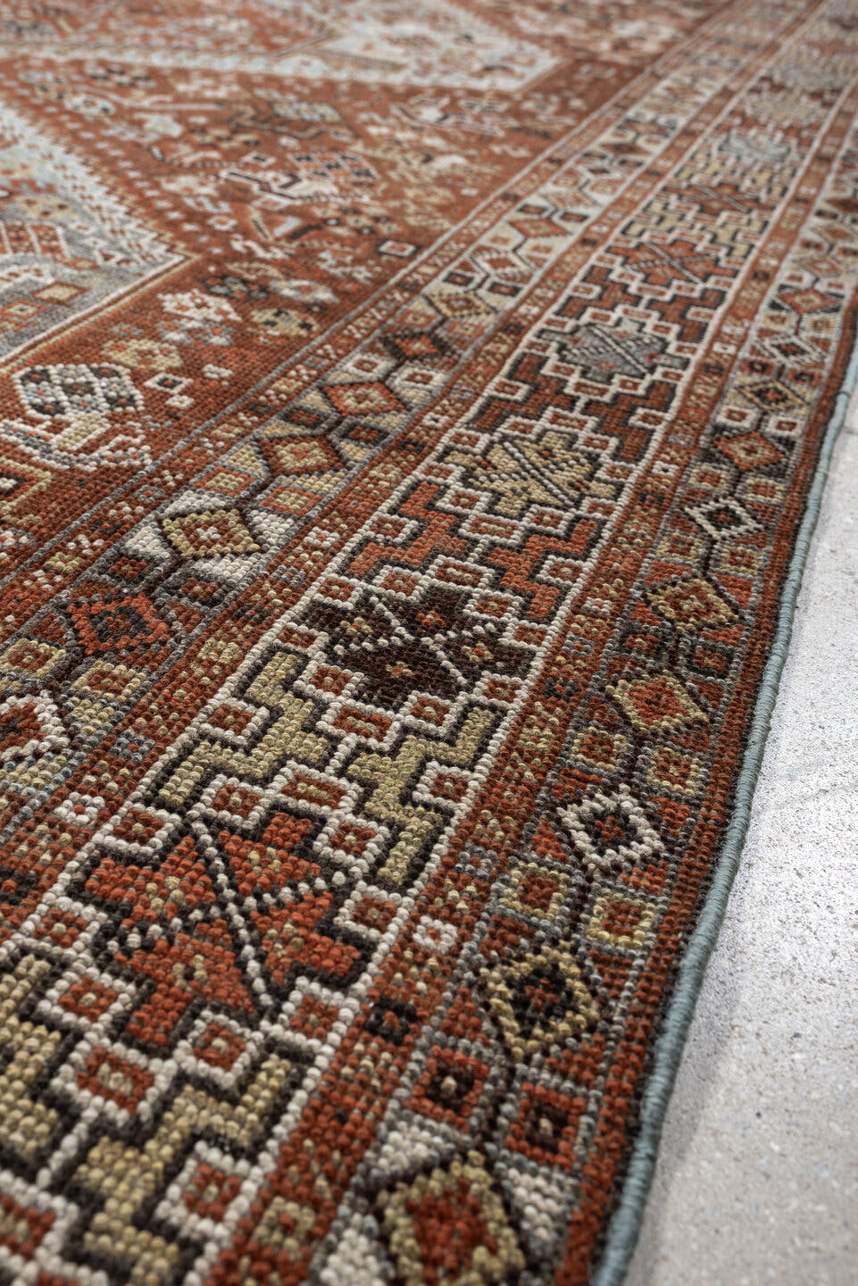 7' x 9' one-of-a-kind handmade antique Shiraz rug. Color palette: rust, pale blue gray, ivory, charcoal, terracotta, camel
